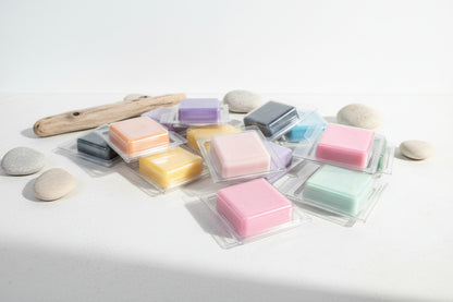 Colorful wax melts in clear packaging on a light surface with stones