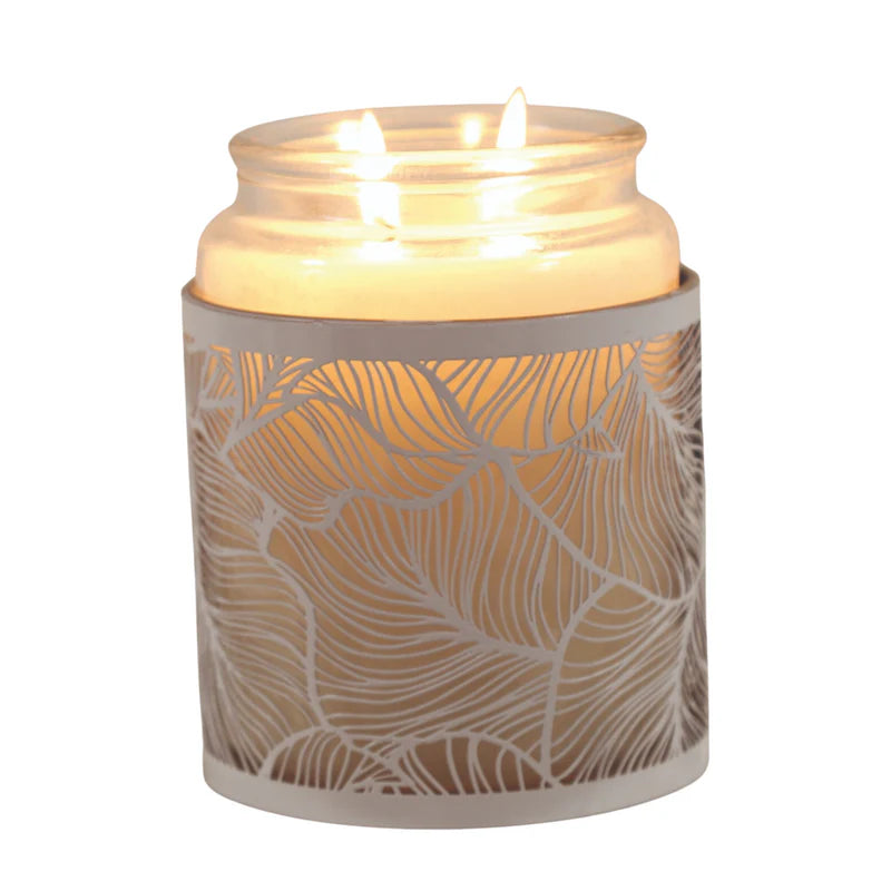 Decorative candle holder with leaf cutout design on a white background