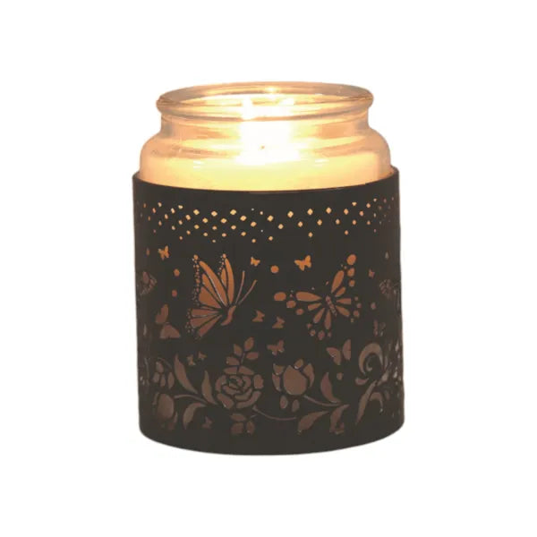 Candle in a decorative holder with butterfly and floral patterns on a white background