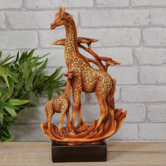 Wooden effect cast resin figurine of two giraffes on a decorative base with a plant and brick wall background
