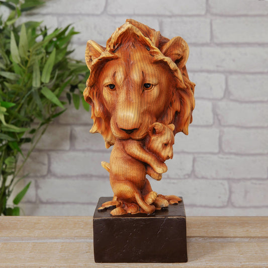 Wood effect cast resin ornament of a lion holding a cub on a marble effect base against a brick wall.