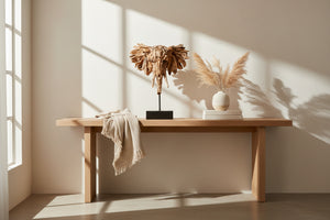 Wooden effect resin elephant head sculpture on a black stand on a wooden console table 