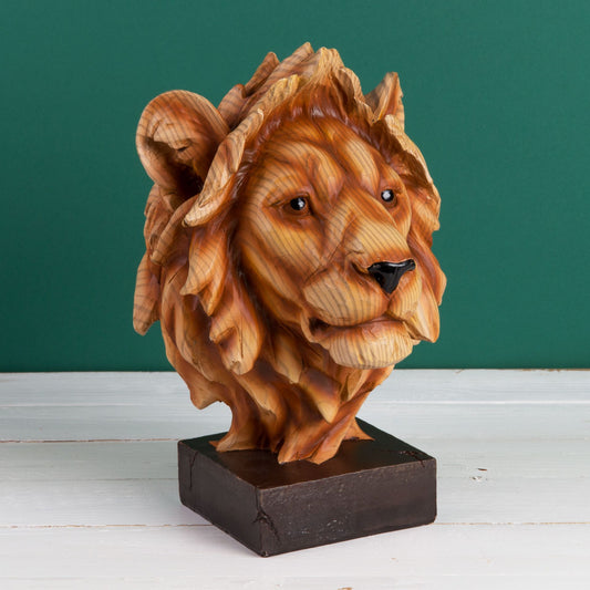 Wooden effect lion head bust on a stand against a green wall.