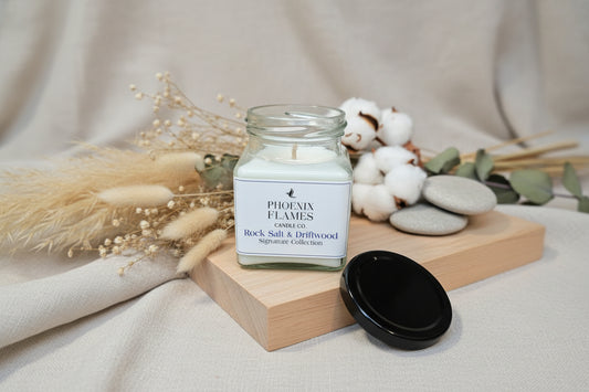 Rock Salt & Driftwood scented jar candle with a label on a wooden surface
