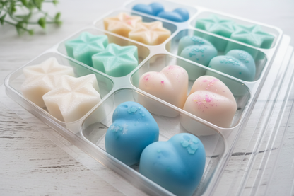 Colorful star-shaped and heart-shaped wax melts in a tray on a light wooden surface.