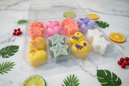 Assorted colourful wax melts in a clear plastic container on a white surface.