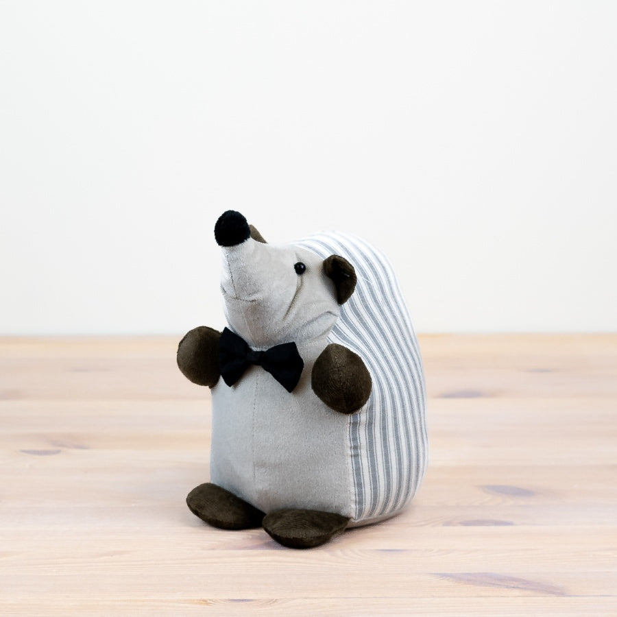 Grey striped hedgehog doorstop on a wooden floor