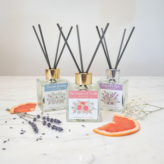 Reed diffuser bottles with short thick dark grey fibre reeds styled on white marble with fresh botanicals